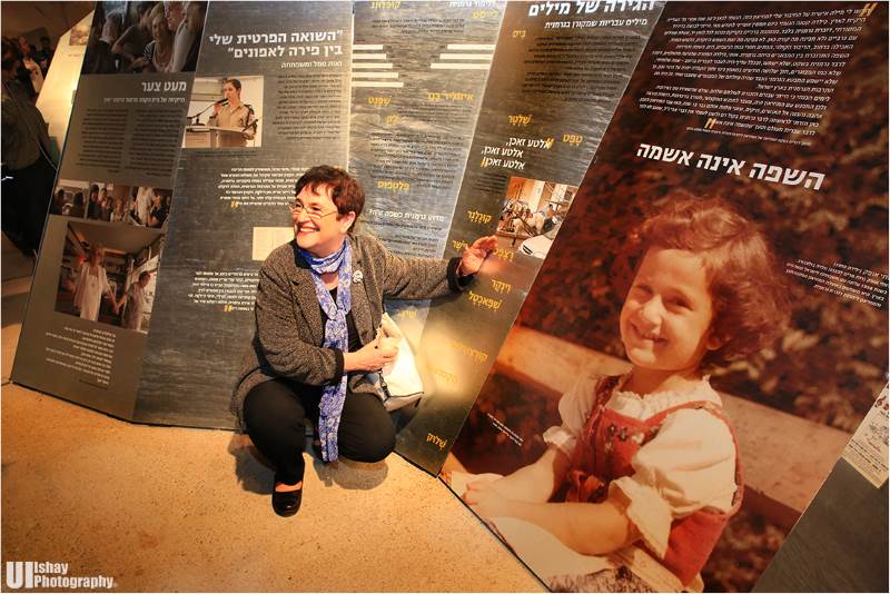 רותי אופק לצד תמונת ילדות שלה עם העלייה ארצה מוינה המוצגת בתערוכה|צילום: UI-ishay photography